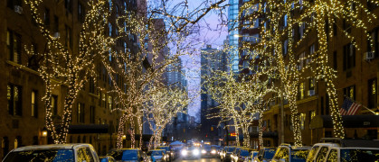 New york city street and brownstone buildings with trees covered in Christmas white lights one point perspective car dusk or early morning stock photo